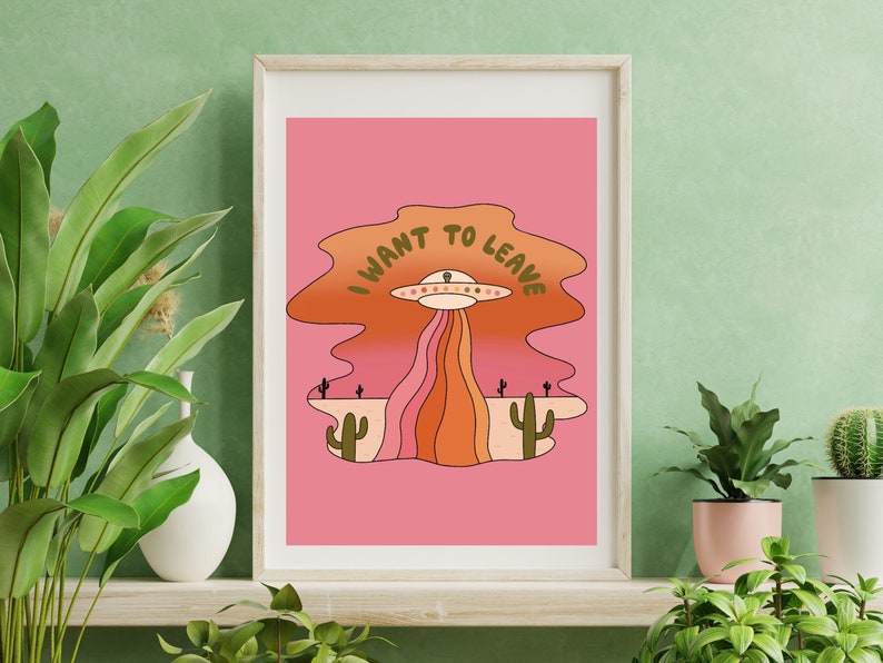 Pu&ograve; includere: Un'illustrazione rosa e arancione di un UFO con il testo "I WANT TO LEAVE" sopra. L'UFO sta volando sopra un paesaggio desertico con cactus.