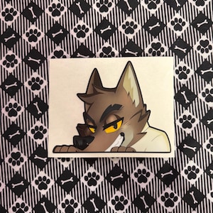 May include: A rectangular sticker featuring a cartoon wolf with brown fur, yellow eyes, and a sly grin. The wolf is wearing a white shirt. The background is a black and white pattern of paw prints and bones.