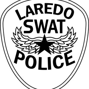 May include: A black and white Laredo SWAT Police badge. The badge features the words "LAREDO SWAT POLICE" in a bold, sans-serif font. A black star is centered above a pair of stylized wings. The badge is outlined in black.