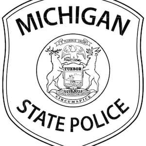 May include: A black and white Michigan State Police badge. The shield-shaped emblem features the words "MICHIGAN STATE POLICE" and a central circular design with the state seal, including the motto "E Pluribus Unum."
