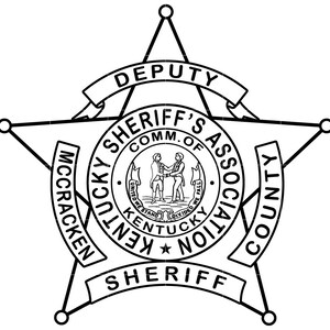 Op de afbeelding: Zwart-witte illustratie van een sheriff-badge met een vijfpuntige ster en de tekst "MCCRACKEN COUNTY KENTUCKY SHERIFF'S ASSOCIATION COMM. OF DEPUTY SHERIFF".
