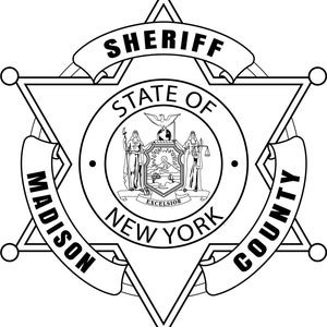 Op de afbeelding: Zwart-wit Sheriff-badge voor Madison County, New York. De badge is een zespuntige ster met het woord "SHERIFF" bovenaan. Het midden heeft een cirkelvormig embleem met de woorden "STATE OF NEW YORK" en een gedetailleerd zegel.