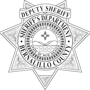 May include: Black and white illustration of a six-pointed star badge with the text "DEPUTY SHERIFF SHERIFF'S DEPARTMENT BERNALILLO COUNTY STATE OF NEW MEXICO BERNALILLO COUNTY" around the perimeter.