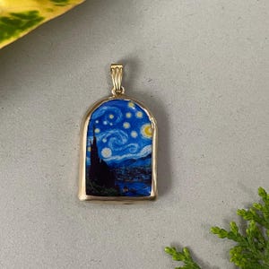 Può includere: Ciondolo dorato con una pittura in miniatura de "La notte stellata" di Van Gogh. L'opera d'arte è incorniciata in un rettangolo con la parte superiore ad arco. Il ciondolo presenta un cielo notturno blu con stelle vorticose e una luna crescente.