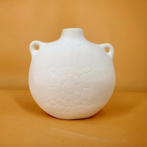 May include: White ceramic vase with two handles and a raised circular design. The vase is a simple, modern design.