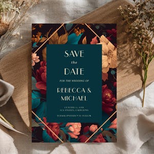 以下が含まれることがあります： 「Save the Date」の文字が白で書かれた、花のウェディング招待状。招待状は、赤、ティール、金のフローラル要素を持つ暗い背景が特徴です。「Rebecca & Michael」の名前も表示されています。招待状は木の板の上にあります。