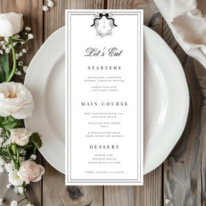 Può includere: Un menù di nozze in bianco e nero con un bordo decorativo e un monogramma. Il menù elenca le opzioni di antipasti, piatti principali e dessert per il ricevimento di nozze. Il testo in fondo al menù recita "Andrea & David | 05.03.20XX".