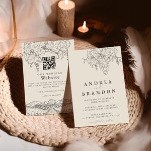 Może przedstawiać: Dwa beżowe zaproszenia ślubne z ilustracjami winorośli. Jedna karta głosi "Our Wedding Website" z kodem QR. Druga karta mówi "Andrea i Brandon" i zaprasza gości do świętowania ich ślubu.