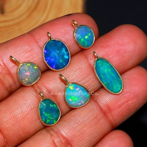 Puede incluir: Varios colgantes de ópalo en diferentes formas, como ovalados y en forma de lágrima. Cada colgante tiene un bisel dorado. Los ópalos muestran un juego de colores, con azules, verdes y destellos de otros colores.