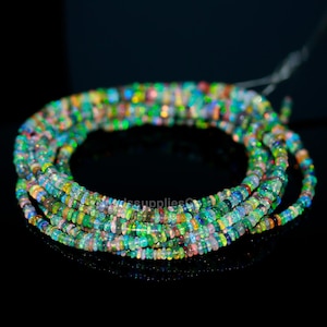 May include: A strand of multi-colored opal beads. The beads are small and round, and they are strung on a thin wire. The beads are a mix of green, blue, pink, and white.