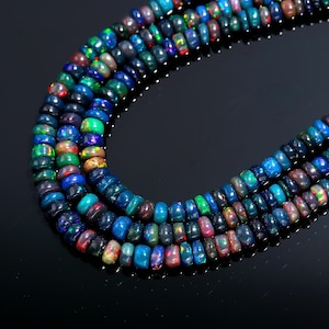 May include: Three strands of black opal beads with a variety of colors including blue, green, red, and yellow. The beads are small and round, strung together to form a necklace.