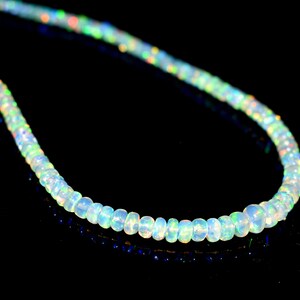 May include: A strand of white opal beads with iridescent rainbow colors. The beads are round and smooth, and the necklace is strung on a clear thread.