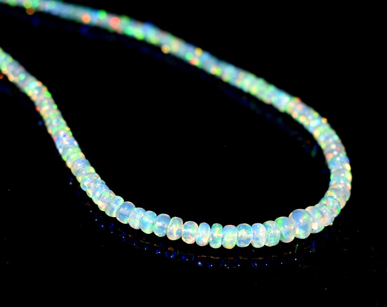 May include: A strand of white opal beads with iridescent rainbow colors. The beads are round and smooth, and the necklace is strung on a clear thread.