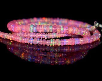 May include: A strand of pink opal beads with iridescent colors. The beads are strung on a silver chain and are arranged in a loose coil.