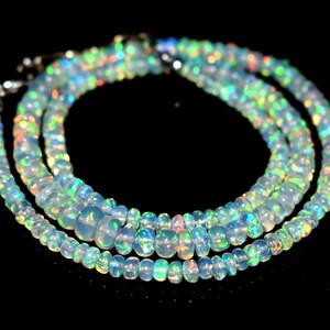 May include: A multi-strand necklace made of iridescent opal beads. The beads are a light blue color with flashes of green, yellow, and orange.