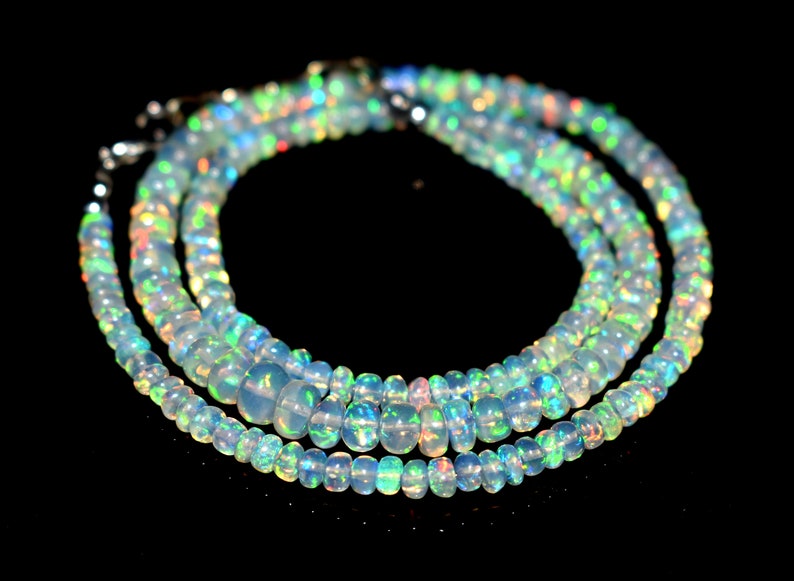 May include: A multi-strand necklace made of iridescent opal beads. The beads are a light blue color with flashes of green, yellow, and orange.