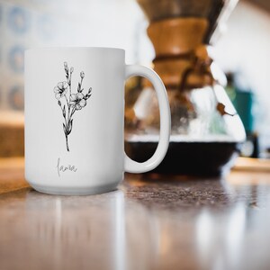 Puede incluir: Taza de cer&aacute;mica blanca con un dibujo de l&iacute;nea negra de una flor y la palabra "lama" impresa en la parte inferior.