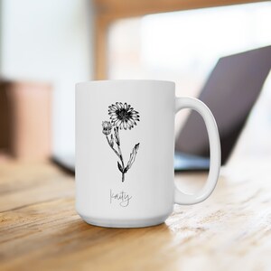 Puede incluir: Taza de cer&aacute;mica blanca con un dibujo en blanco y negro de una margarita y el nombre "Kaity" escrito en cursiva.
