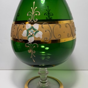 May include: A white ceramic mug with a black handle and the text "But First, Coffee" in a bold, black font. The mug is set against a blurred background, suggesting a cozy setting.