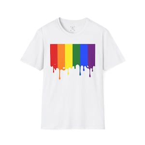 Op de afbeelding: Wit T-shirt met een regenboogontwerp met een druipend verfeffect. Het ontwerp bevat verticale strepen in rood, oranje, geel, groen, blauw en paars. Het shirt heeft een ronde hals en korte mouwen.