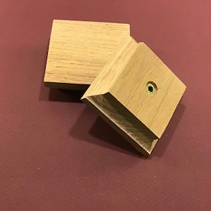 Peut inclure: Deux blocs de bois, l'un avec un trou au centre, sont empilés l'un sur l'autre. Les blocs sont en bois brun clair et ont une finition lisse.