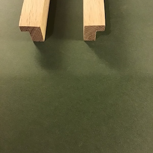 May include: Two pieces of unfinished, light brown wood with a T-shaped end. The wood is likely oak.