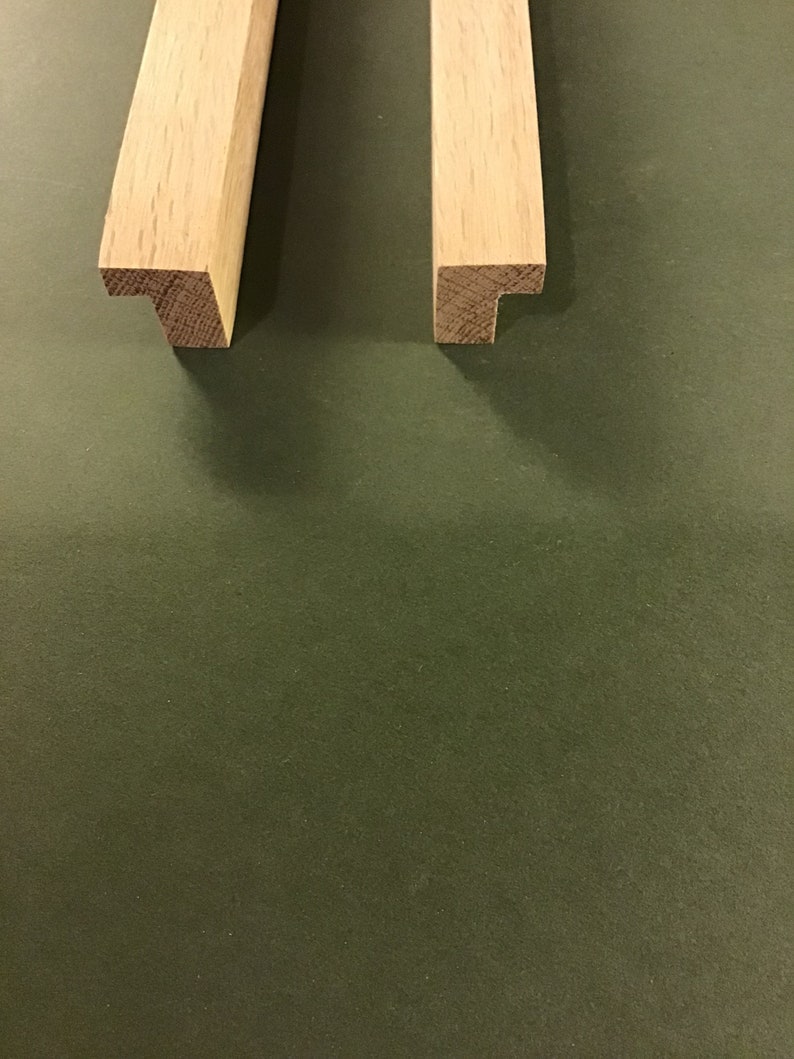 May include: Two pieces of unfinished, light brown wood with a T-shaped end. The wood is likely oak.