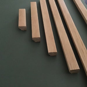 May include: Five pieces of unfinished wood trim in various sizes, arranged in a fan shape on a dark green surface.