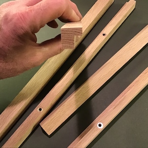 May include: Four wooden strips with rounded edges and pre-drilled holes. The strips are light brown in colour and appear to be made of oak.