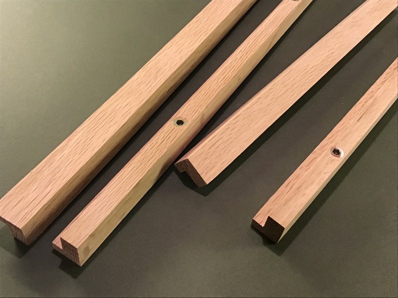 May include: Four wooden pieces with angled edges and a small hole drilled in each piece. The pieces are light brown in colour and appear to be part of a wooden frame.