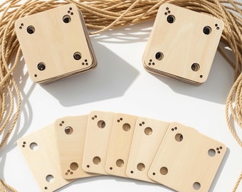 May include: Two stacks of square light-colored wooden tiles with rounded corners, each featuring four circular holes and small decorative dot patterns in the corners, arranged alongside six individual tiles and a coiled length of tan rope.
