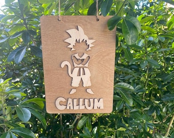 Puede incluir: Un letrero de madera con un recorte de personaje de dibujos animados de una persona con el pelo de punta y un cinturón. El nombre "CALLUM" está escrito debajo del personaje.