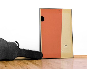 May include: A framed abstract art print with a black circle and musical symbols, leaning against a white wall. A black guitar case rests on a wooden floor. The artwork features orange and beige vertical sections.