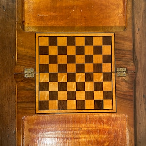 Peut inclure: Un plateau de jeu en bois avec un motif de damier incrusté au centre. Le plateau a deux couvercles à charnières qui s'ouvrent pour révéler le damier.