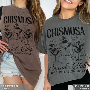 Two models in Comfort Colors brand shirt with graphic of Chismosa Social Club in color black. Ovesized shirts in colors espresso & pepper.