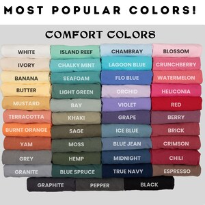 May include: A chart showing the most popular comfort colors for t-shirts. The colors are arranged in columns, with the names of each color listed below. The colors include white, ivory, banana, butter, mustard, terracotta, burnt orange, yam, grey, granite, graphite, pepper, black, island reef, chalky mint, seafoam, light green, bay, khaki, sage, moss, hemp, blue spruce,  chambray, lagoon blue, flo blue, orchid, violet, grape, ice blue, blue jean, midnight, true navy, blossom, crunchberry, watermelon, heliconia, red, berry, brick, crimson, chili, espresso.