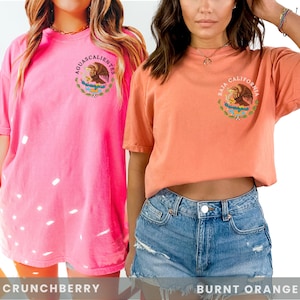 Two models in Comfort Colors brand shirt with graphic of Mexican Coat of Arms personalizable with mexico states. Ovesized shirts in colors crunchberry & burnt Orange.