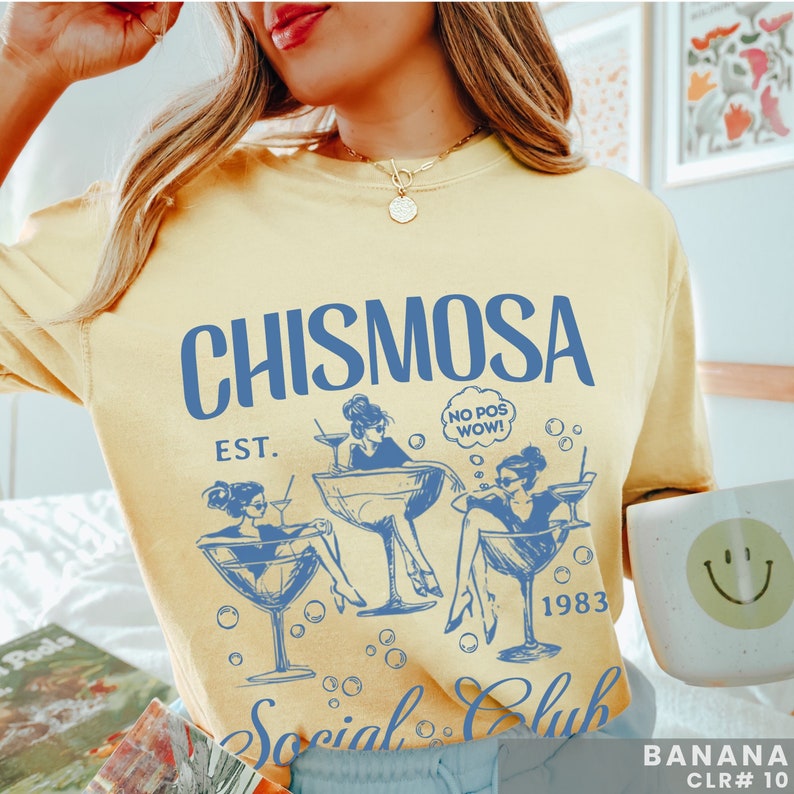 May include: A yellow t-shirt with a blue graphic design that says "CHISMOSA EST. 1983 Social Club". The graphic features three women in cocktail glasses with the text "NO POS WOW!" in a speech bubble.