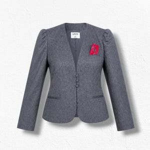 May include: A charcoal gray blazer featuring a collarless neckline, long sleeves with gathered shoulders, and three fabric-covered buttons down the front. A bright pink pocket square is tucked into the left chest pocket. The label reads KASPER 4L.