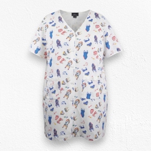 May include: White short-sleeved tunic with a V-neck and two front pockets. The tunic is covered in a repeating pattern of colorful French bulldog illustrations. The illustrations include blue, red, and brown bulldogs.