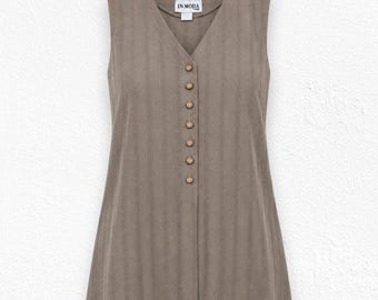 Può includere: Un gilet senza maniche color tortora con scollo a V e una trama a righe verticali. La parte anteriore è chiusa da sette piccoli bottoni rotondi marrone chiaro. Un'etichetta bianca all'interno del collo riporta la scritta IN MODA.