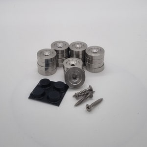 以下が含まれることがあります： 黒いゴムパッドが底に付いた銀色の金属製家具脚10個セット。脚は2個と3個のグループに積み重ねられています。黒いゴムパッド4個と銀色のネジ3本も含まれています。