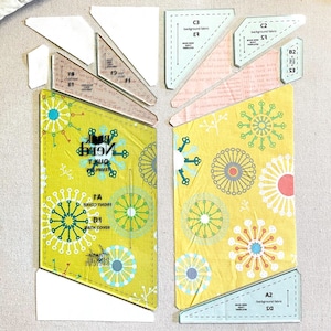 May include: A set of clear plastic quilting templates with various shapes and sizes. The templates are labelled with letters and numbers, and include instructions for a quilt project called "Book Nerd Quilt Templates".