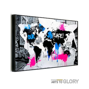 May include: A black and white world map with blue and pink paint splatters. The words "OUR PLACE!" are written in black on the map. The map is framed in a black frame.