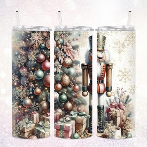 May include: A set of three stainless steel tumblers with straws. The tumblers feature festive Christmas designs. One has a Christmas tree with ornaments and gifts, another a nutcracker, and the third has snowflakes.