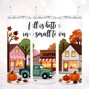May include: White 20 oz tumbler with a fall-themed design. The design features a small town scene with a green truck, pumpkins, and the text "Fall is better in a small town."