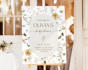 May include: A rectangular welcome sign for a baby shower featuring a central oval with the text WELCOME TO OLIVIA'S babyshower 10.12.2023 THANK YOU SO MUCH FOR CELEBRATING WITH US! surrounded by watercolor illustrations of wildflowers.