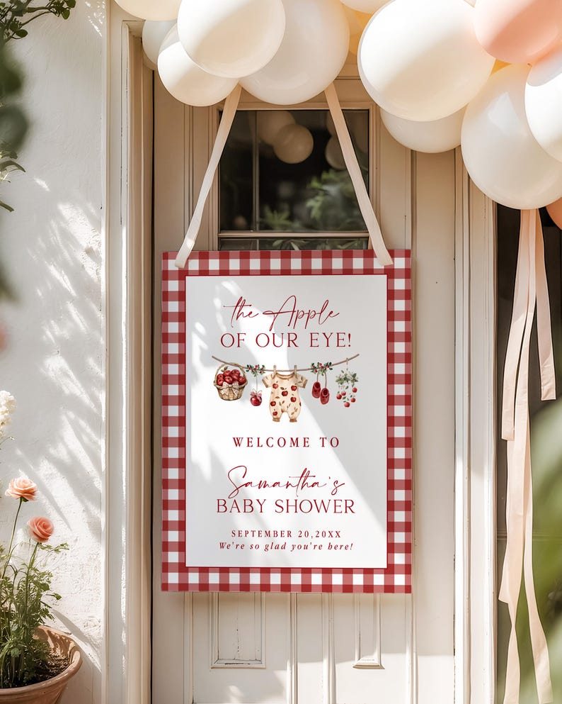 Puede incluir: Un letrero rectangular de baby shower con un borde de cuadros rojos y blancos. El letrero dice "the Apple of Our Eye!" y "Welcome to Samantha's Baby Shower" con la fecha y un mensaje de bienvenida. Decorado con ilustraciones de beb&eacute;.