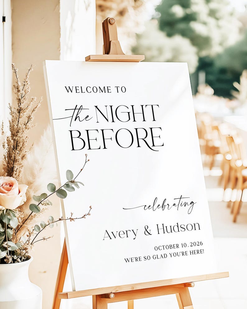 Pu&ograve; includere: Un cartello di benvenuto bianco su un cavalletto di legno. Il cartello recita "WELCOME TO The NIGHT BEFORE celebrating Avery & Hudson OCTOBER 10, 2026 WE'RE SO GLAD YOU'RE HERE!" in nero.