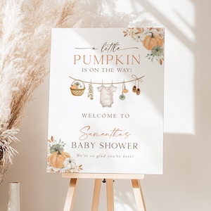 May include: A white rectangular sign featuring the text A little PUMPKIN IS ON THE WAY! WELCOME TO Samantha's BABY SHOWER We're so glad you're here! The design includes watercolor illustrations of pumpkins, a basket, baby clothes, and shoes.